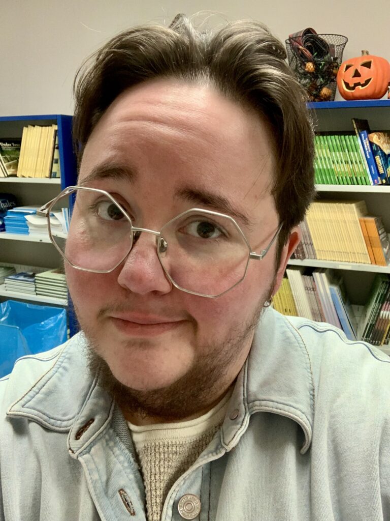 Jes Davey, a smiling white man with brown hair and wireframe glasses. 